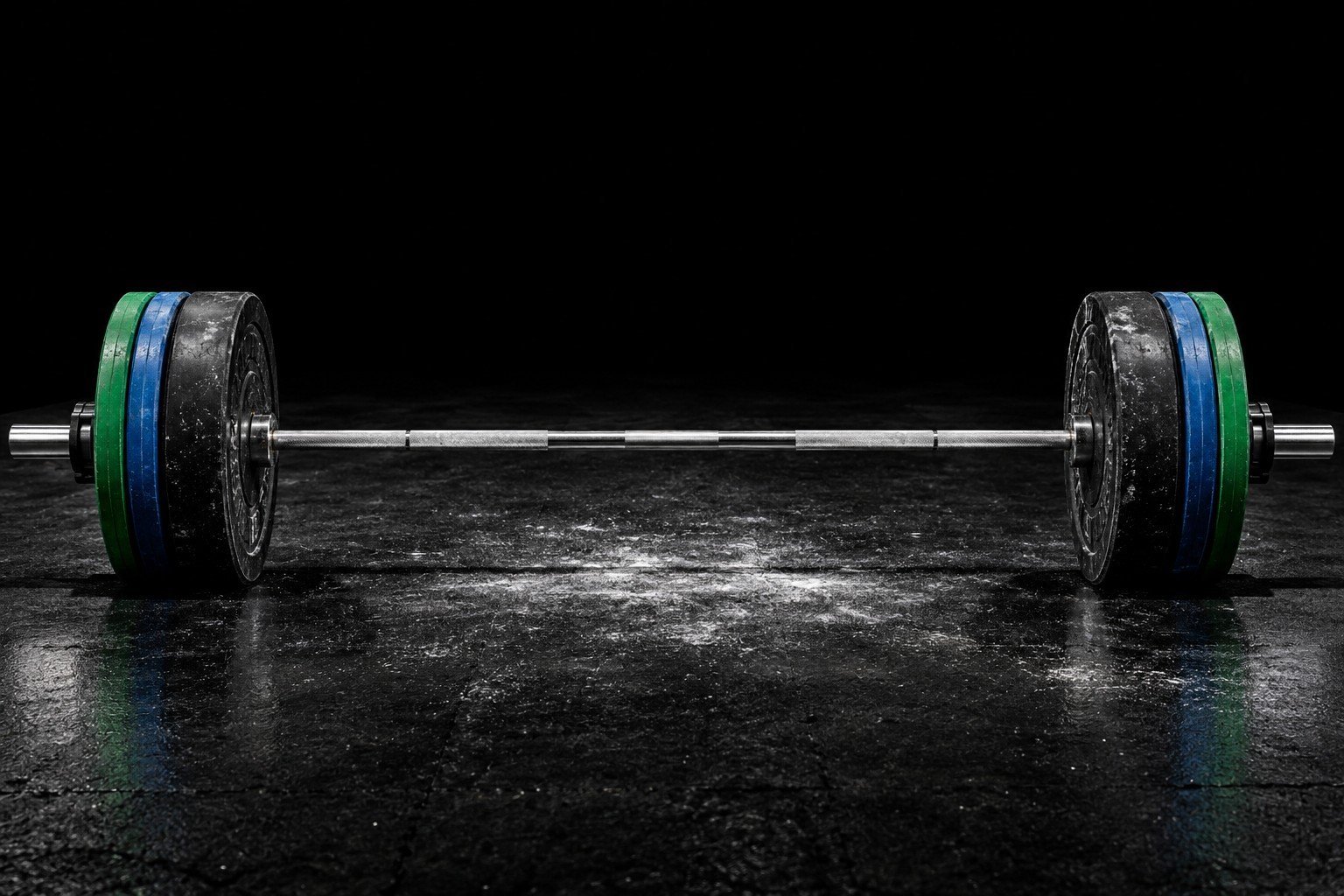 Worn barbell and bumper plates on a chalk-marked black rubber floor